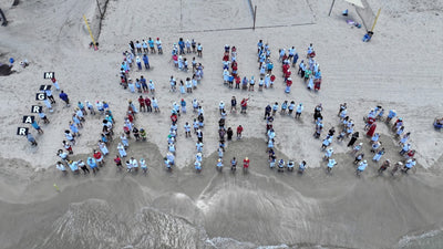 Migrar es un derecho: más de 200 personas forman frase en la playa en acto solidario con las comunidades inmigrantes